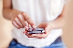 blurred image of a person holding and using a mobile phone