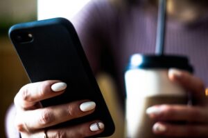 Person using a mobile phone and drinking coffee