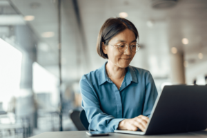 woman sitting at a laptop and typing on a keyboard